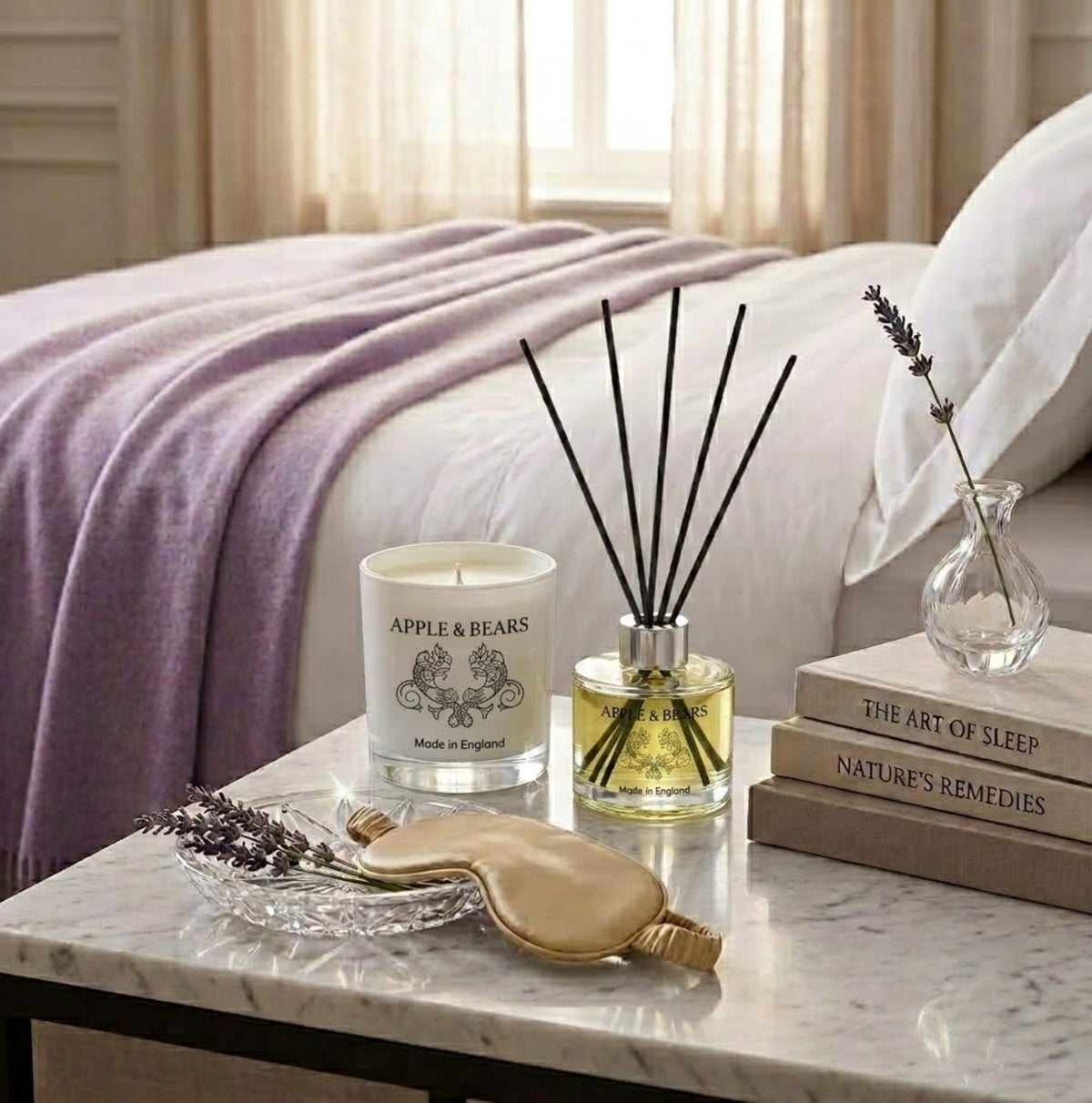 Apple & Bears Lavender Home Fragrance Gift Set with Soy Wax Candle and Reed Diffuser on a marble bedside table with silk sleep mask, lavender sprigs and wellness books in a luxury bedroom, Made in England