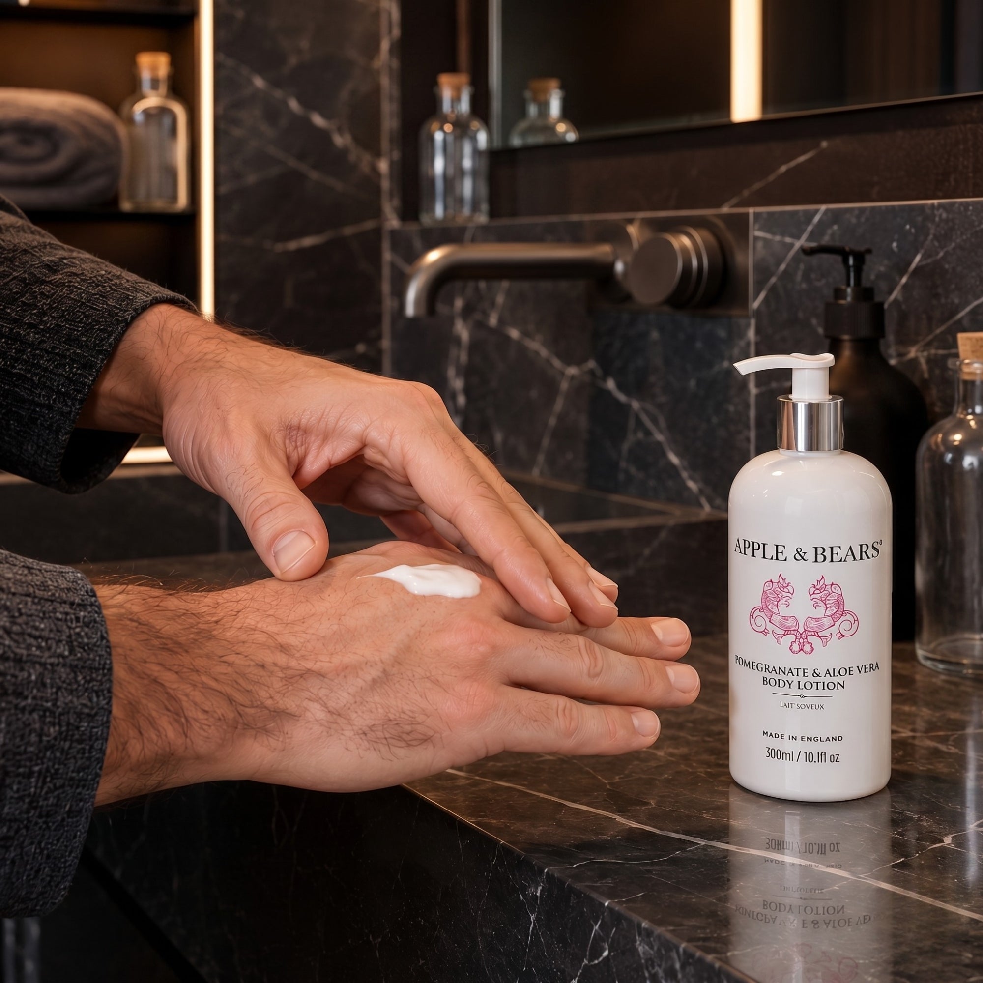Apple and Bears Pomegranate and Aloe Vera Body Lotion 300ml hands applying lotion in luxury dark marble bathroom made in England