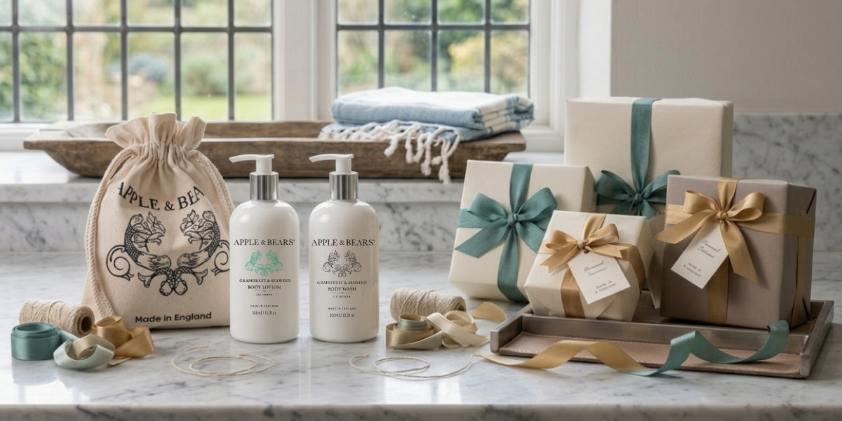 APPLE & BEARS Grapefruit & Seaweed body lotion and body wash bottles with a branded eco-cotton drawstring bag and elegantly wrapped gift boxes with ribbon, styled on a marble surface