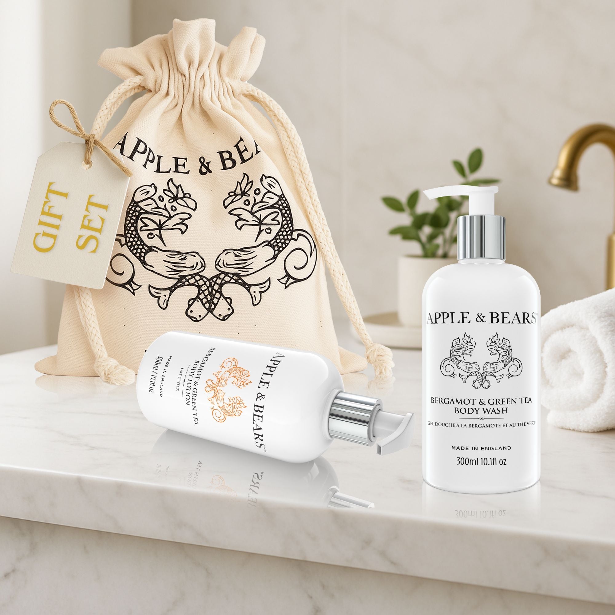 Luxury Apple and Bears Bergamot and Green Tea body care gift set featuring a signature body wash bottle and body lotion on a white marble countertop next to an elegant canvas drawstring gift bag.