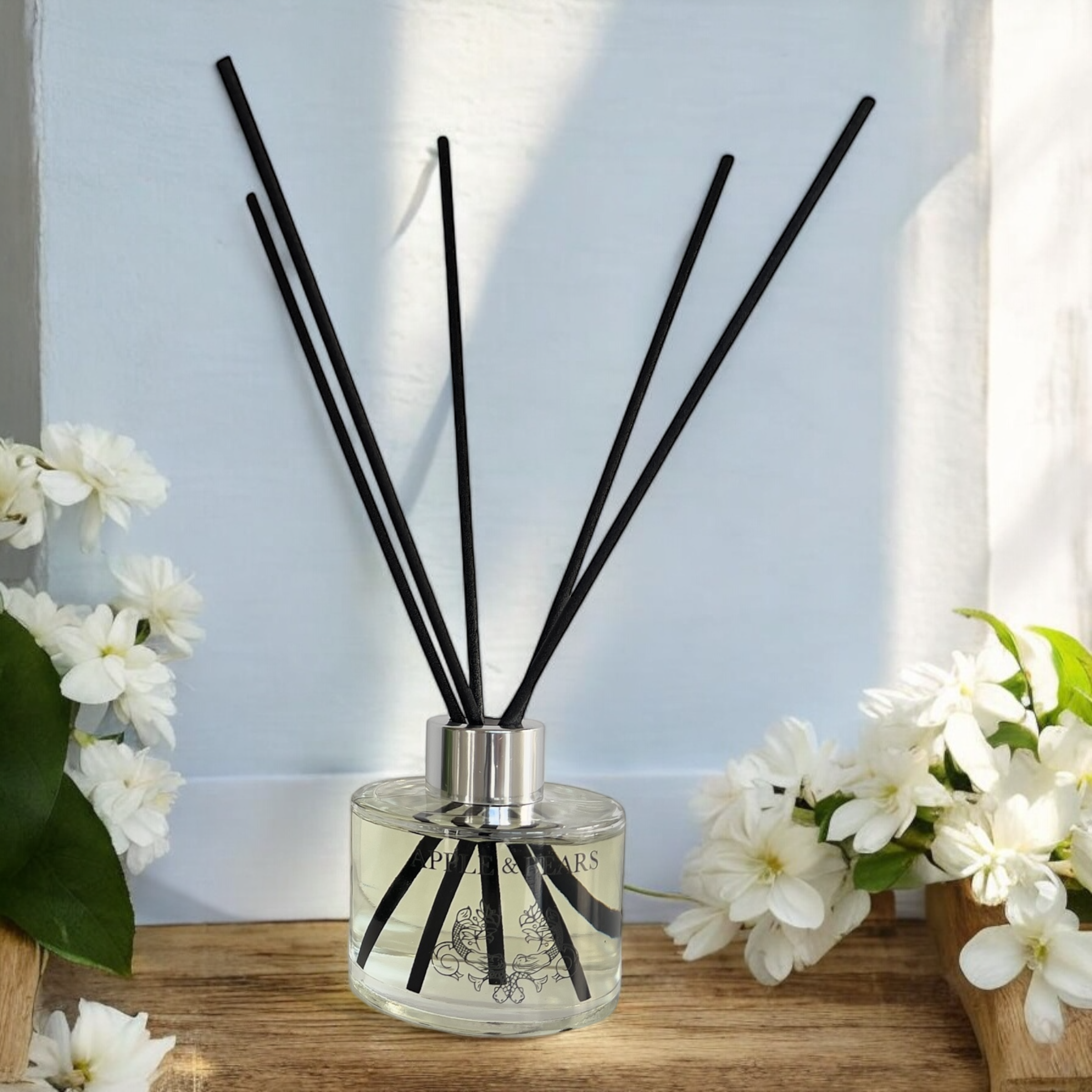 Jasmine Zen Luxury Reed Diffuser in a bright floral setting - Long-lasting home fragrance with black rattan reeds, hand-poured in England by Apple & Bears.