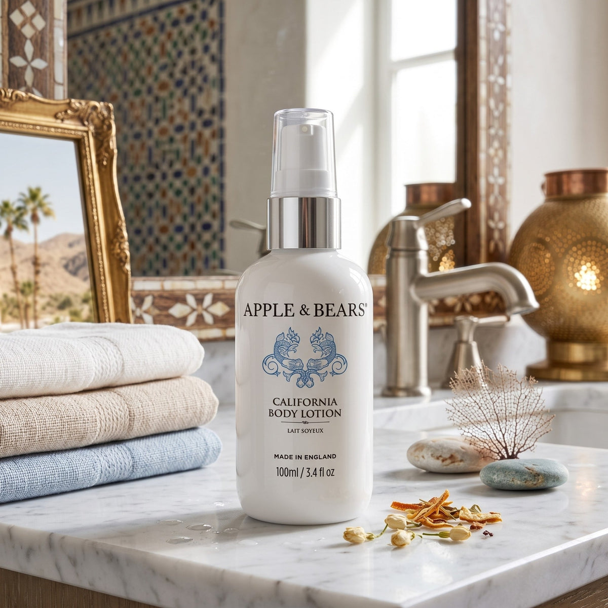 Apple & Bears California Body Lotion 100ml travel size on marble bathroom counter with Moroccan tiles, gold lantern and folded towels — travel body lotion made in England