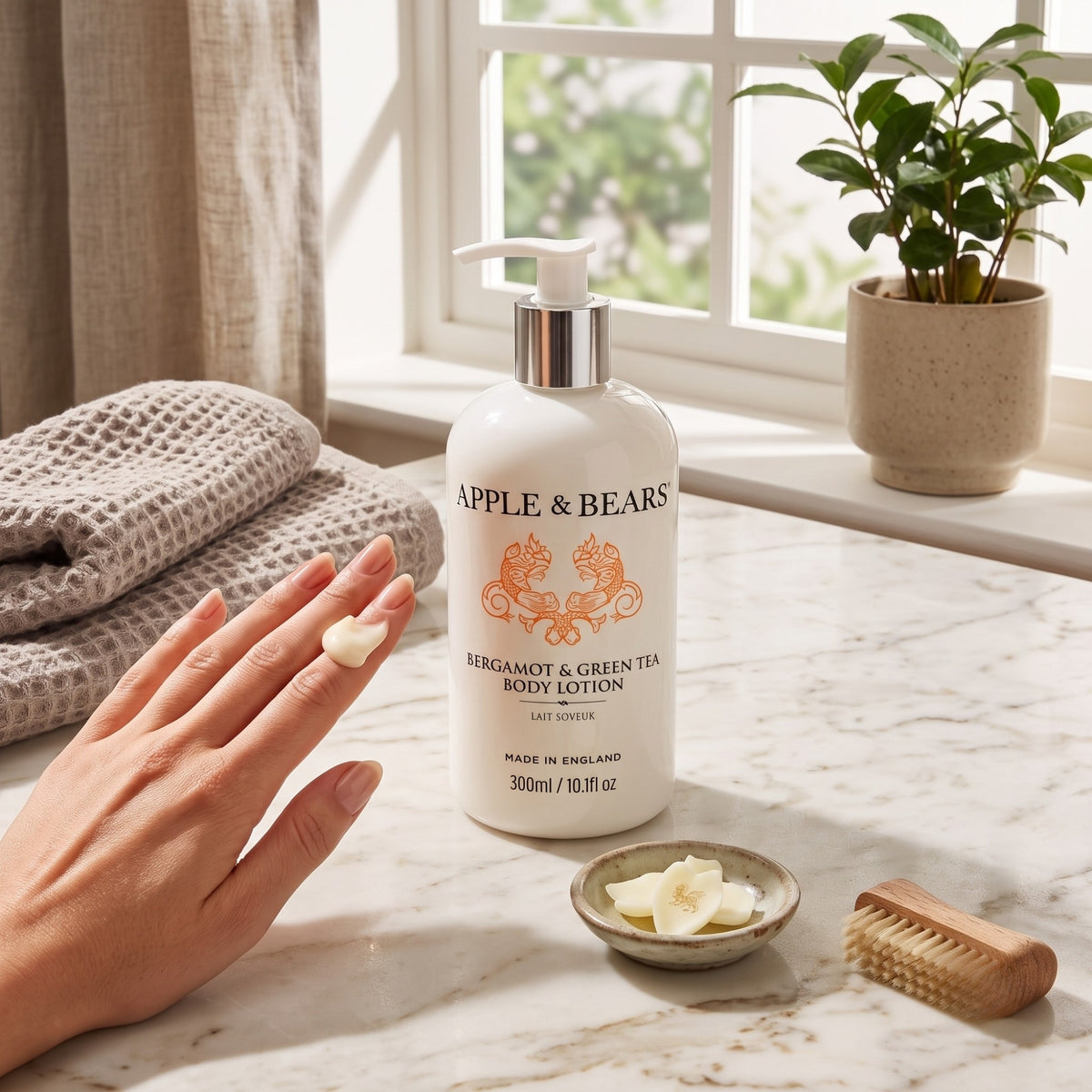Apple & Bears Bergamot & Green Tea Body Lotion 300ml on a marble bathroom counter with folded towels, botanical details and a wooden brush — natural vegan body lotion for dry skin, made in England
