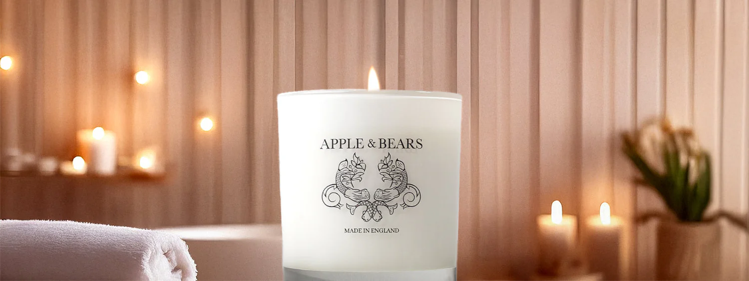 An Apple and Bears eco-luxury clean-burning soy wax scented candle elegantly lit in a modern, serene home interior setting.