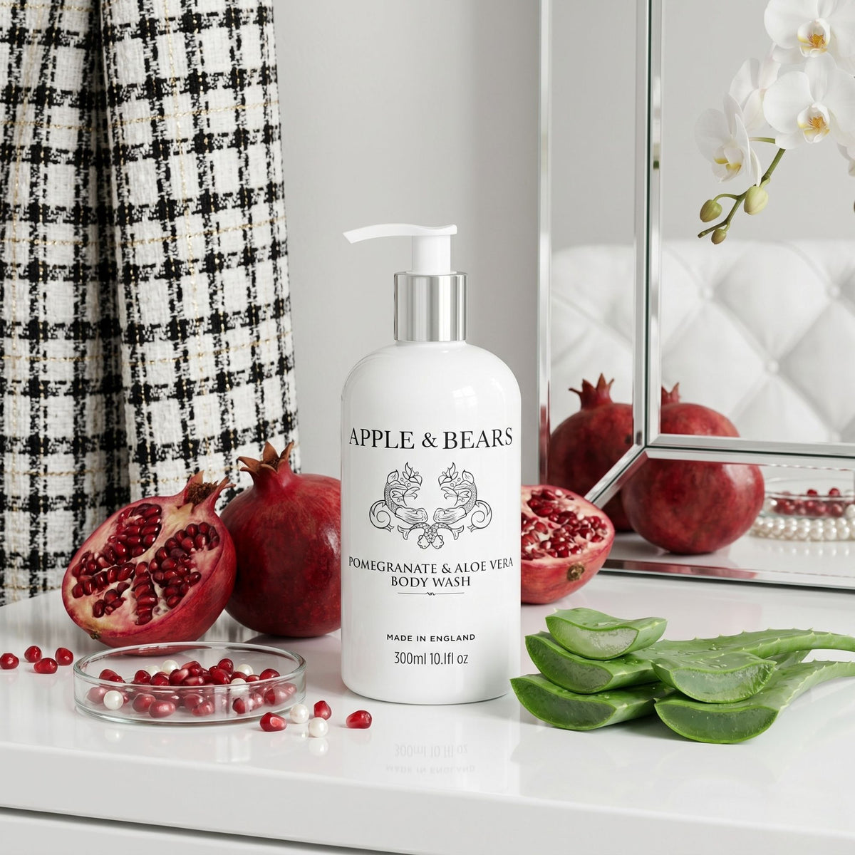 Apple & Bears Pomegranate & Aloe Vera Body Wash 300ml on a white vanity with fresh pomegranate halves and aloe vera leaves — natural sulphate-free body wash, made in England
