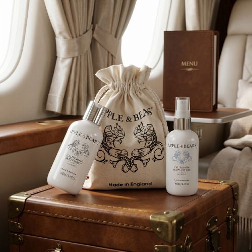 Apple &amp; Bears California Citrus Travel Set with eco cotton drawstring bag on vintage leather trunk inside private jet cabin - luxury natural travel skincare Made in England
