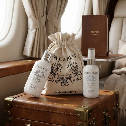 Apple &amp; Bears California Citrus Travel Set with eco cotton drawstring bag on vintage leather trunk inside private jet cabin - luxury natural travel skincare Made in England
