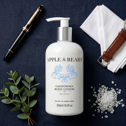 Apple and Bears California Body Lotion 300ml flat lay on navy linen with eucalyptus sea salt fountain pen and leather watch strap made in England