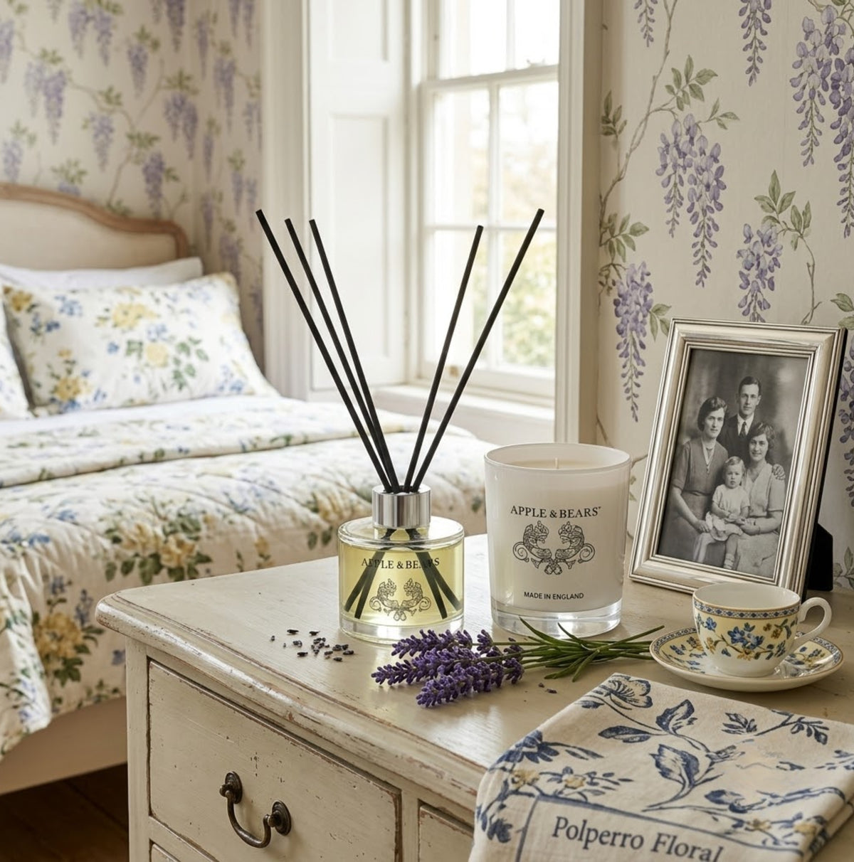 Apple &amp; Bears Lavender Home Fragrance Gift Set with Reed Diffuser and Soy Wax Candle on a painted vintage bedside table with fresh lavender sprigs, vintage family portrait and English bone china teacup in a country bedroom with wisteria wallpaper, Made in England