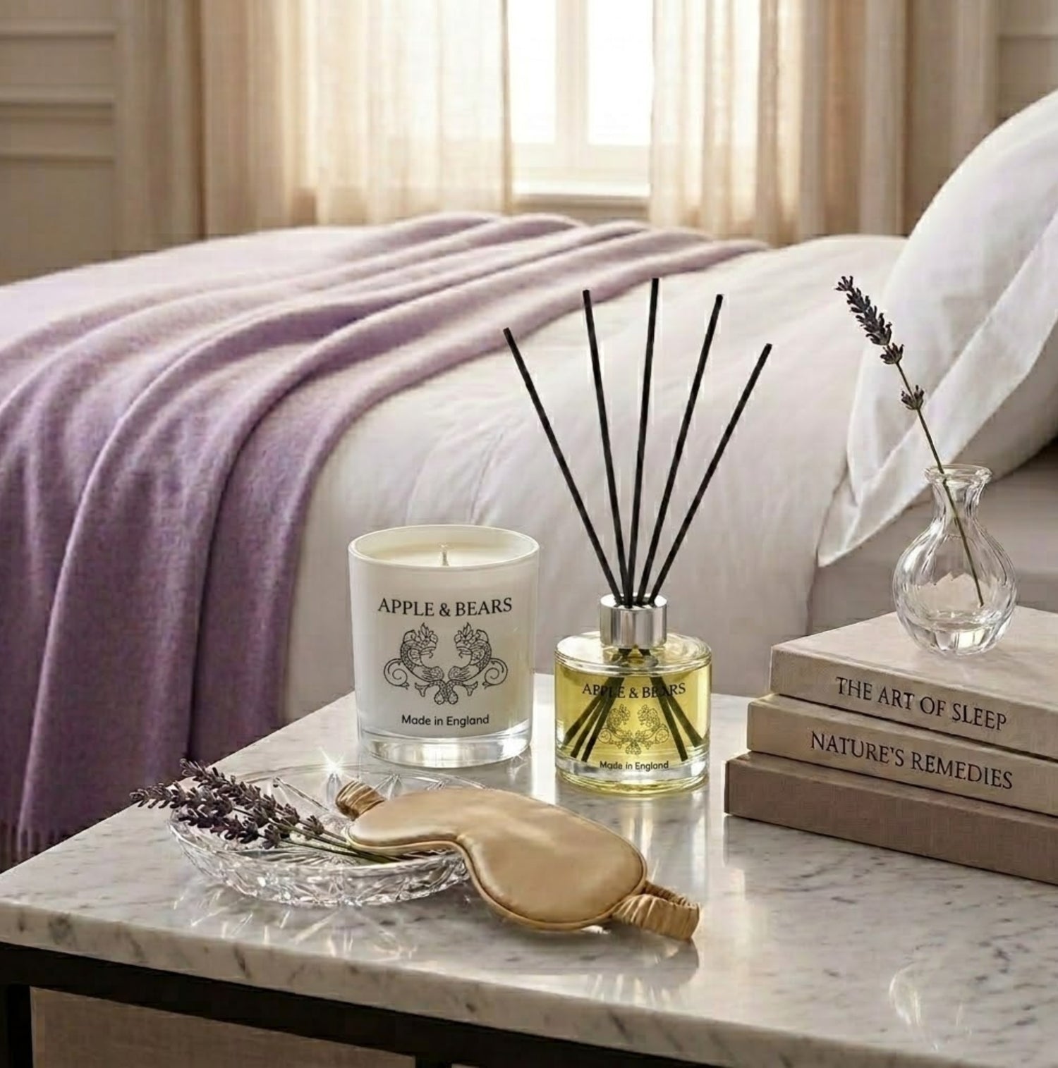 Apple &amp; Bears Lavender Home Fragrance Gift Set with Soy Wax Candle and Reed Diffuser on a marble bedside table with silk sleep mask, lavender sprigs and wellness books in a luxury bedroom, Made in England