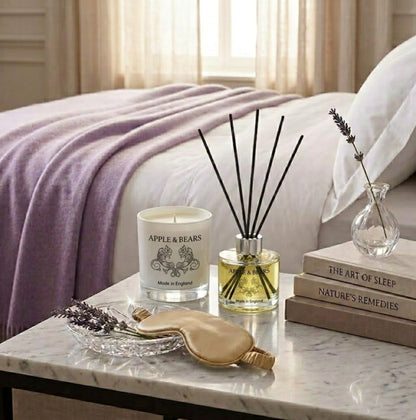 Apple &amp; Bears Lavender Home Fragrance Gift Set with Soy Wax Candle and Reed Diffuser on a marble bedside table with silk sleep mask, lavender sprigs and wellness books in a luxury bedroom, Made in England
