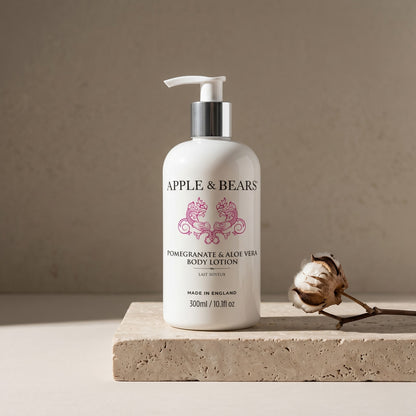 Apple and Bears Pomegranate and Aloe Vera Body Lotion 300ml on stone plinth with pomegranate and aloe vera editorial lifestyle made in England