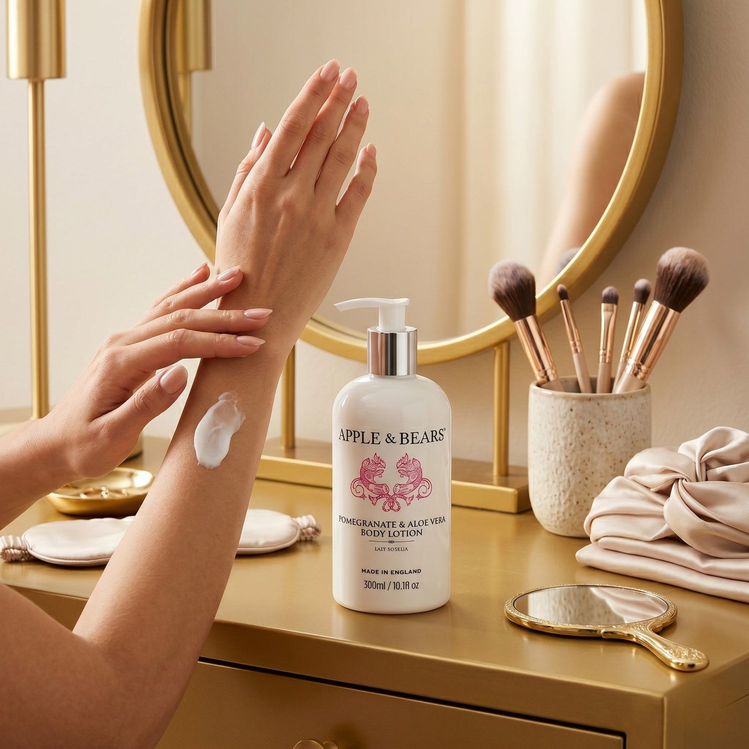 Apple and Bears Pomegranate and Aloe Vera Body Lotion 300ml hands applying lotion at gold vanity dressing table with round mirror and makeup brushes made in England
