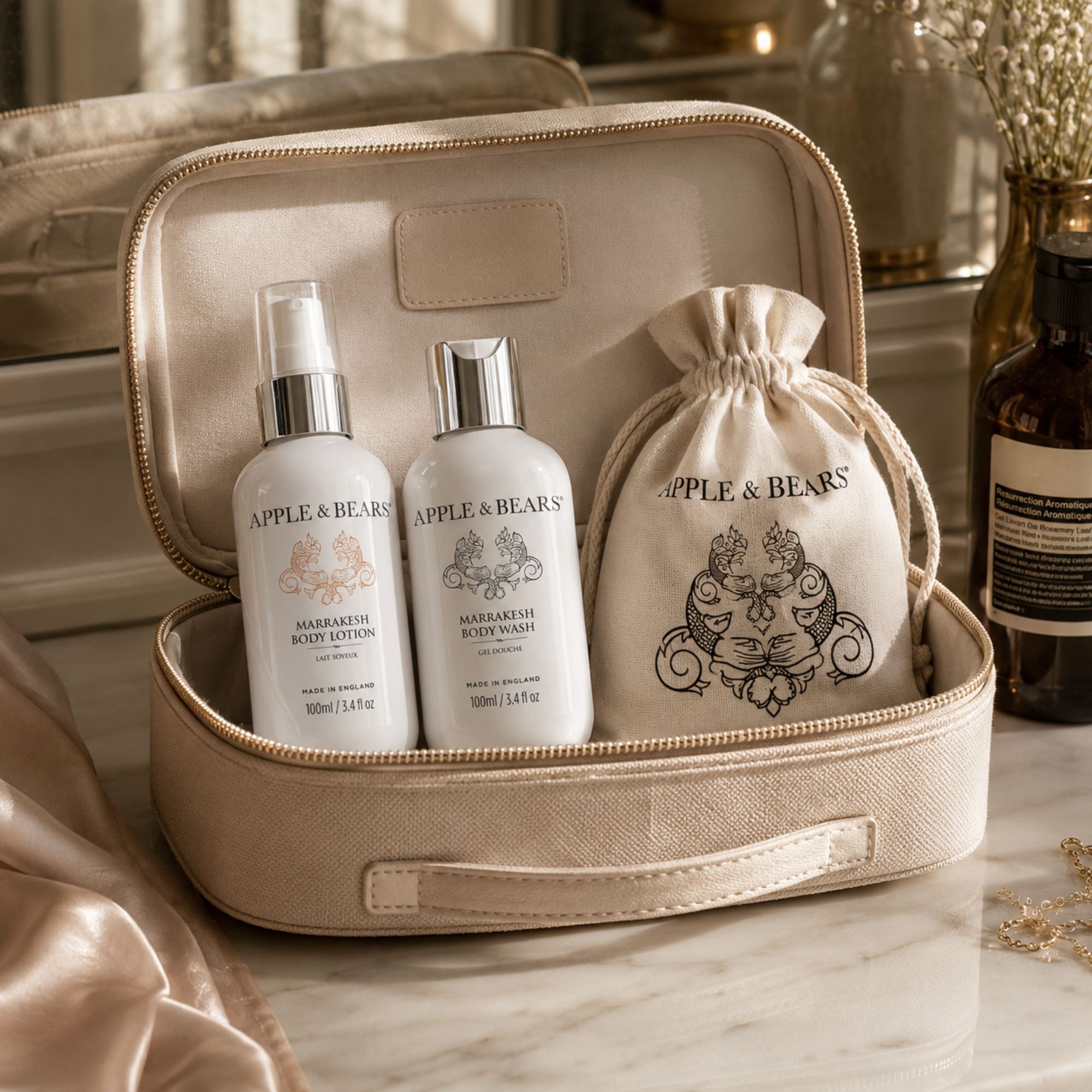 Apple &amp; Bears Marrakesh Travel Gift Set 100ml/3.4 fl oz with eco cotton drawstring bag displayed in open beige zip vanity case with gold hardware on marble counter, Made in England